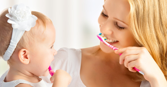 mother and daughter baby girl brushing their teeth together